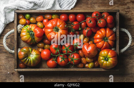 Heirloom tomatoes colorés dans le bac en bois rustique en bois foncé sur arrière-plan, Vue de dessus, composition horizontale Banque D'Images