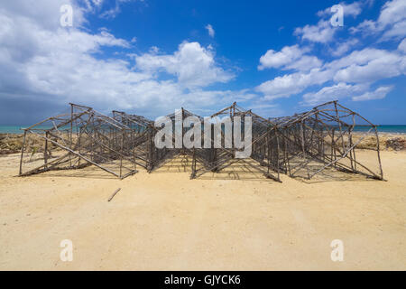 Des pots en bois fait main prête pour la pêche sont empilés sur la plage en Guadeloupe Banque D'Images