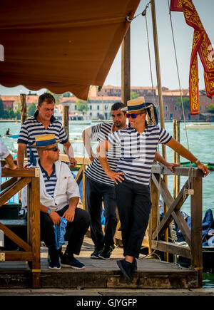 4 hommes portant des gondoliers à rayures traditionnelles robes chapeaux canotier de paille, d'attente pour les passagers. Venise, Italie. Banque D'Images