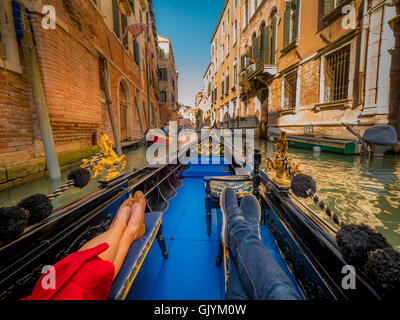 Homme et femme jambes reposant sur un siège dans une gondole, sur un canal à Venise. L'Italie. Banque D'Images