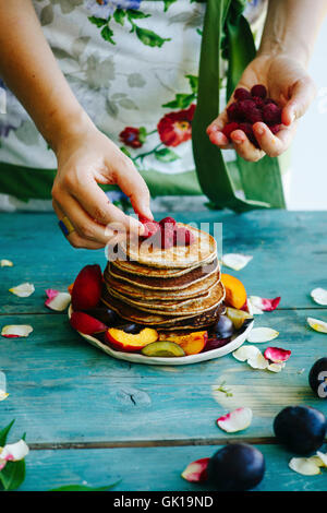 Girl putting framboises sur le dessus de crêpes Banque D'Images