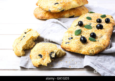 Pain italien frais avec l'olive, l'ail et fines herbes. Pain focaccia italienne maison traditionnelle sur la serviette en lin. Banque D'Images