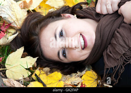 Jeune femme couchée dans les feuilles d'automne Banque D'Images