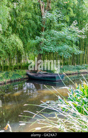 Portrait format image d'eau tranquille scène avec une paire de vieux bateaux en bois vert sur un étang entouré d'arbres et de feuillages Banque D'Images