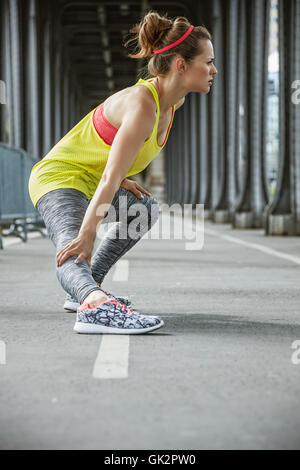 Remise en forme en plein air à Paris. Jeune femme active qui s'étend sur le Pont de Bir-Hakeim pont de Paris Banque D'Images