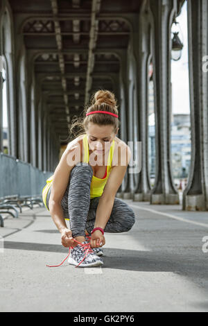 Remise en forme en plein air à Paris. Les jeunes de la sportive attacher ses lacets sur Pont de Bir-Hakeim pont de Paris Banque D'Images