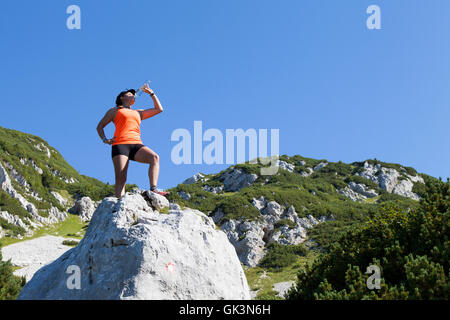 Boissons trekker femme haut dans les montagnes Banque D'Images