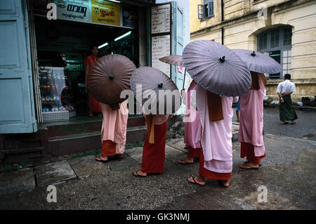 Ca. 2000, Yangon, Birmanie --- Un groupe de nonnes bouddhistes mendie l'aumône dans les magasins un jour de pluie à Yangon (Rangoon), le Myanmar. --- Im Banque D'Images