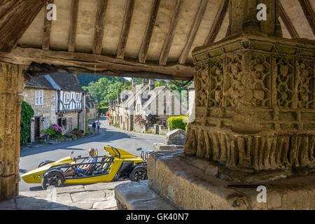 L'Angleterre, dans le Wiltshire, Castle Combe, vue sur village & voiture de Market Cross Banque D'Images