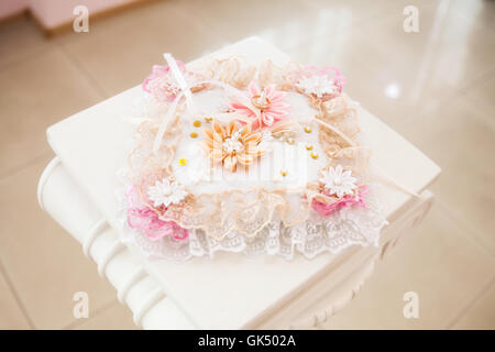 Les anneaux de mariage en or blanc sur l'oreiller décorées de fleurs Banque D'Images