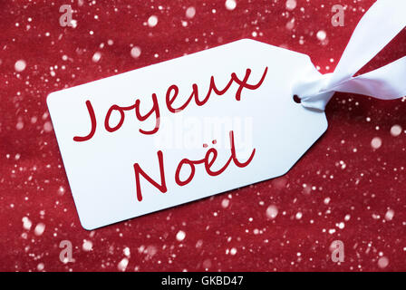 Étiquette sur fond rouge, flocons, Joyeux Noel signifie Joyeux Noël Banque D'Images