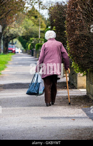 Vieille Dame balade shopping accueil et à l'aide de bâton de marche Banque D'Images