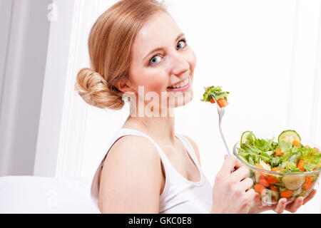 Laughing young woman eating healthy salad Banque D'Images