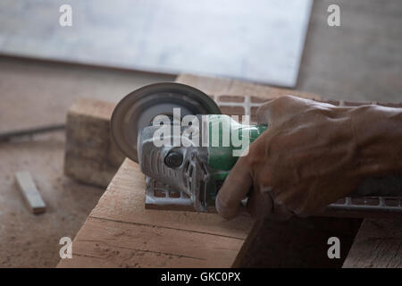 Worker cutting une tuile à l'aide d'une meuleuse at construction site Banque D'Images