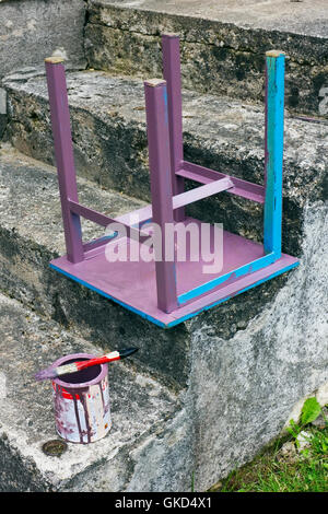 Nous peindre un tabouret bleu en rose avec de la peinture à l'huile sur un porche en béton de la maison rurale Banque D'Images