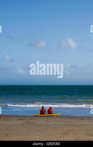 Une image sereine de plage de Tenby montrant deux sauveteurs en gardant une veille sur les eaux. Banque D'Images