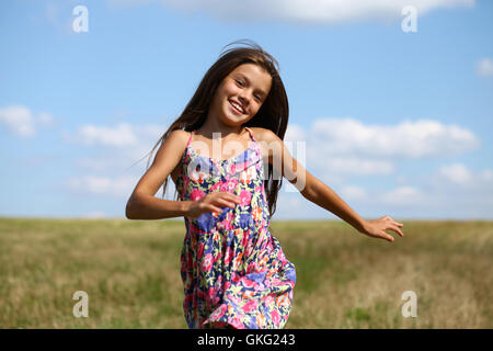 Happy little girl s'exécutant en champ d'été Banque D'Images