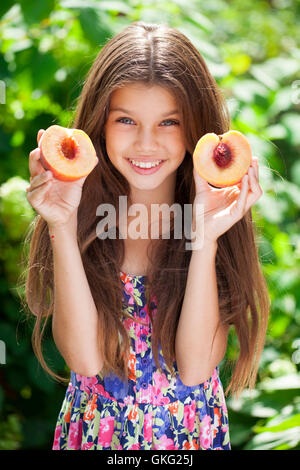 Portrait d'une jeune brunette petite fille avec pêche, piscine d'été Banque D'Images