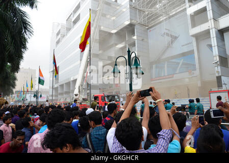 Bangladeshis se rassemblent pour surveiller les opérations de secours à l'extérieur du Bashundhara City shopping mall qui a pris feu à Dhaka, au Bangladesh. Le 21 août, 2016 quatorze unités du Service des incendies s'efforcent de contrôler la flamme. L'incendie a éclaté à shop 360 sur le bloc C de la Mall qui est un magasin de chaussures. L'incendie a éclaté vers 11h25 et soudain se répandre sur l'étage, a déclaré Abdur Rahman, au service de l'agent de service d'incendie de la salle de contrôle. Banque D'Images