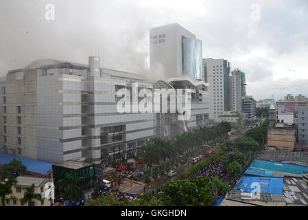 Bangladeshis se rassemblent pour surveiller les opérations de secours à l'extérieur du Bashundhara City shopping mall qui a pris feu à Dhaka, au Bangladesh. Le 21 août, 2016 quatorze unités du Service des incendies s'efforcent de contrôler la flamme. L'incendie a éclaté à shop 360 sur le bloc C de la Mall qui est un magasin de chaussures. L'incendie a éclaté vers 11h25 et soudain se répandre sur l'étage, a déclaré Abdur Rahman, au service de l'agent de service d'incendie de la salle de contrôle. Banque D'Images