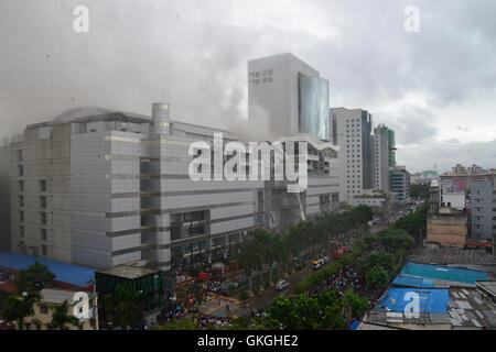 Bangladeshis se rassemblent pour surveiller les opérations de secours à l'extérieur du Bashundhara City shopping mall qui a pris feu à Dhaka, au Bangladesh. Le 21 août, 2016 quatorze unités du Service des incendies s'efforcent de contrôler la flamme. L'incendie a éclaté à shop 360 sur le bloc C de la Mall qui est un magasin de chaussures. L'incendie a éclaté vers 11h25 et soudain se répandre sur l'étage, a déclaré Abdur Rahman, au service de l'agent de service d'incendie de la salle de contrôle. Banque D'Images