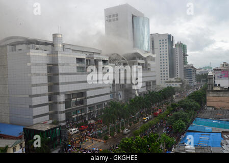 Bangladeshis se rassemblent pour surveiller les opérations de secours à l'extérieur du Bashundhara City shopping mall qui a pris feu à Dhaka, au Bangladesh. Le 21 août, 2016 quatorze unités du Service des incendies s'efforcent de contrôler la flamme. L'incendie a éclaté à shop 360 sur le bloc C de la Mall qui est un magasin de chaussures. L'incendie a éclaté vers 11h25 et soudain se répandre sur l'étage, a déclaré Abdur Rahman, au service de l'agent de service d'incendie de la salle de contrôle. Banque D'Images