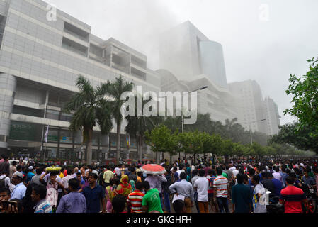 Bangladeshis se rassemblent pour surveiller les opérations de secours à l'extérieur du Bashundhara City shopping mall qui a pris feu à Dhaka, au Bangladesh. Le 21 août, 2016 quatorze unités du Service des incendies s'efforcent de contrôler la flamme. L'incendie a éclaté à shop 360 sur le bloc C de la Mall qui est un magasin de chaussures. L'incendie a éclaté vers 11h25 et soudain se répandre sur l'étage, a déclaré Abdur Rahman, au service de l'agent de service d'incendie de la salle de contrôle. Banque D'Images