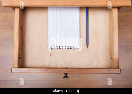 Vue de dessus du stylo bleu et squared ordinateur portable dans n'ouvrir le tiroir de la table de nuit Banque D'Images