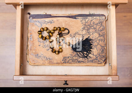 Vue de dessus du rosaire sur livre ansient dans tiroir de table de nuit Banque D'Images