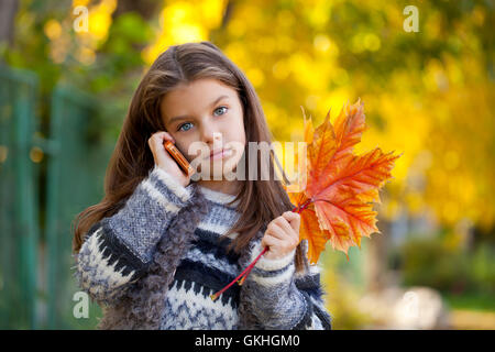 Belle jeune fille de l'école d'talking on mobile phone dans l'autumn park Banque D'Images