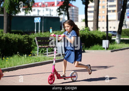 Petite fille monter le scooter dans le parc Banque D'Images