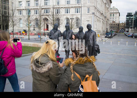 Les femmes qui prenez des photos sur la sculpture statue Beatles à Pier Head sur Liverpools waterfront Banque D'Images