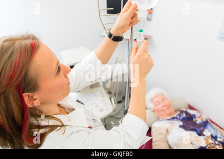 Médecin senior clinique met un goutte-à-goutte Banque D'Images