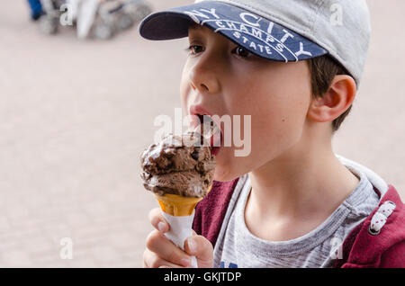 Un jeune garçon jouit d'une glace au chocolat. Banque D'Images