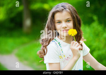 Petite fille qui sent un pissenlit jaune au printemps park Banque D'Images