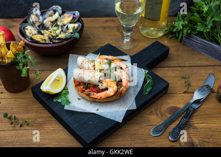 Cuisine italienne. Bruschetta avec les calmars et les crevettes, les tomates et le persil Banque D'Images