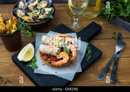 Cuisine italienne. Bruschetta avec les calmars et les crevettes, les tomates et le persil Banque D'Images