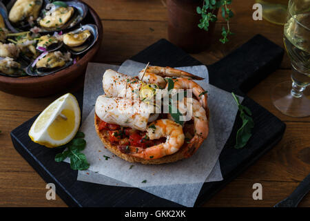 Tapas aux crevettes et calmars sur planche de bois, de haut. Banque D'Images