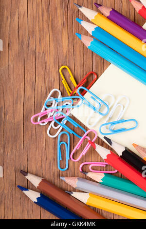 Ensemble de crayons de couleur et des trombones sur un fond de bois Banque D'Images