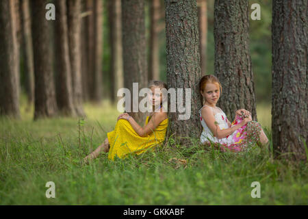 Deux petites amies posant assis dans la forêt de pins. Banque D'Images