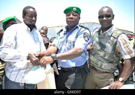 Bashir Mohamed, représentant des personnes aveugles dans le camp anciennement reçoit le don de denrées alimentaires provenant de l'AMISOM, Benoît, Eseigbe et officier de liaison humanitaire Senior, Abdul Diabagate, à un camp de personnes déplacées, Siliga Amerikanka, le 24 février 2014. Ce don composé de 10 sacs de riz, 3 sacs de maïs, 3 sacs de niébé, 3 sacs de sucre, de sel et de 20 gallons d'huile. Banque D'Images