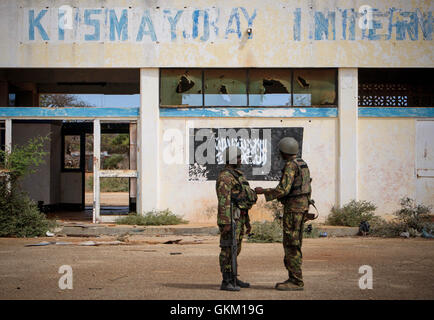 La SOMALIE, Kismayo : Dans un document publié par la photographie Union africaine-ONU de l'équipe de support d'information le 02 octobre, les soldats du contingent Kenyan avec la Mission de l'Union africaine en Somalie (AMISOM) sont devant le drapeau noir de l'affilié à Al Qaïda groupe extrémiste Al Shabaab peint sur le mur de l'aéroport de Kismayo. Les troupes de l'AMISOM Kenyan dans et par Kismayo, le dernier grand bastion urbain de tAl Shabaab, sur leur route vers l'aéroport sans un coup de feu à la suite d'une intervention de deux mois pour libérer les villes et villages du sud de la Somalie et Banque D'Images