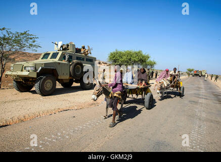 La SOMALIE, Buur-Hakba : Dans un document de cours photographie prise et publiée par l'Union africaine et l'équipe de support d'information des Nations Unies 27 février 2012, les civils somaliens ride cours des soldats ougandais servant avec la Mission de l'Union africaine en Somalie (AMISOM) dans le centre de la ville somalienne d'Buur-Hakba. L'armée nationale somalienne (SNA) pris en charge par les forces de l'AMISOM capturé la ville d'importance stratégique sur le Afgooye-Baidoa dans le corridor de la région de la Baie d'Al-Qaeda groupe extrémiste affiliés à Al Chabaab tôt ce matin sans résistance, marquant ainsi une perte importante pour le groupe. La ville, situé à 64 kms à l'Est Banque D'Images