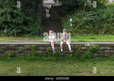 Deux enfants sont assis sur la plate-forme d'une gare désaffectée sur le sentier Monsal dans le Peak District, Derbyshire Banque D'Images