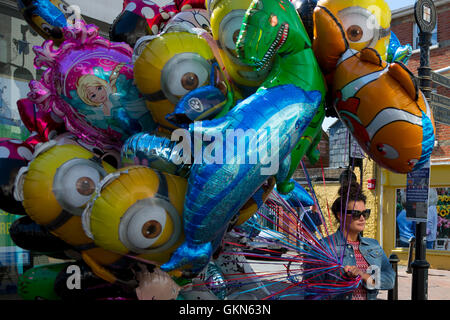 Marchande de ballons d'Artifice vendredi soir, rue La Semaine de Cowes sur les jouets pour enfants Souris Mini Île de Wight drôle de visage Cartoon Disney hélium lunettes thème femme hautaine Banque D'Images