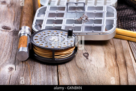 Vue en gros de mobilier fly reel, Rod, et l'atterrissage avec net lure conteneur sur planches de bois rustique. Selective focus sur le tambour. Banque D'Images