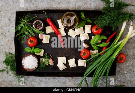 Ravioles aux herbes et des légumes pour la cuisson sur un vieux fond sombre. Vue d'en haut Banque D'Images