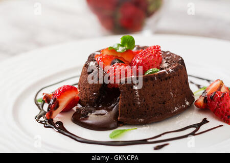 Fondant au chocolat (Cupcake) avec des fraises et du sucre en poudre Banque D'Images