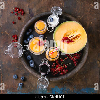 Variété de melon et de bleuets smoothie dans des bocaux en verre et bouteille avec le yogourt et petits fruits groseille rouge, servi dans l'ancien bac d'argile ov Banque D'Images