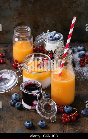 Variété de melon et de bleuets smoothie dans des bocaux en verre et bouteille avec le yogourt et petits fruits groseille rouge, servi plus vieux dark woode Banque D'Images